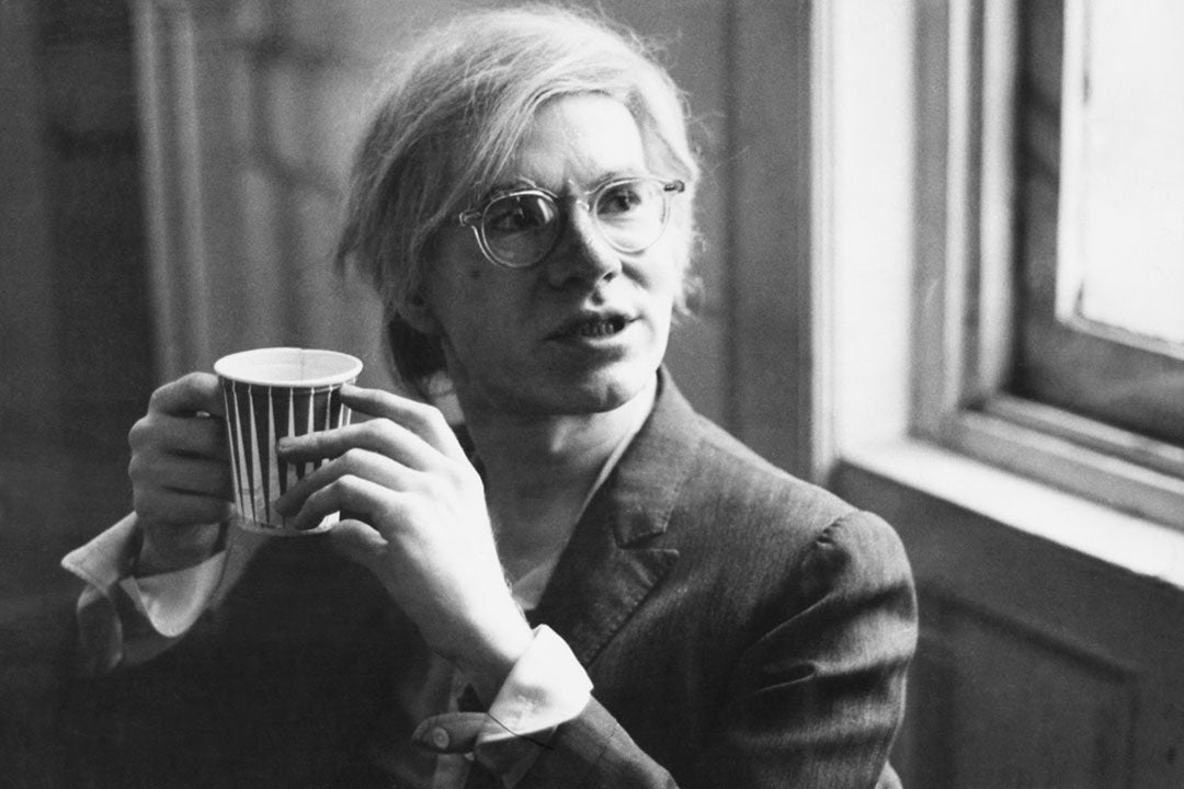 Andy-Warhol-drinking-coffee-wearing-a-suit-and-clear-glasses-frame.jpg
