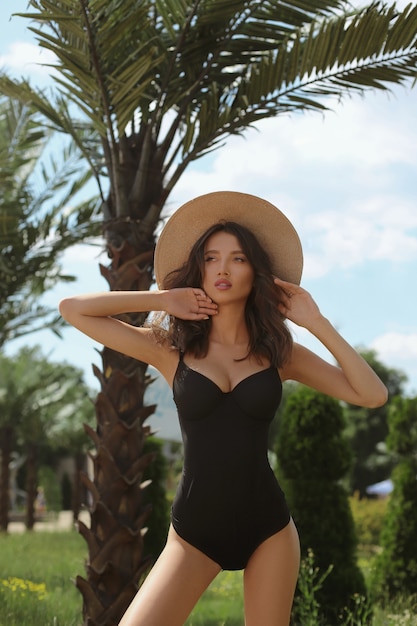 gorgeous-young-woman-with-tanned-sexy-body-black-bikini-straw-hat-enjoying-summertime-near-palm-trees_179135-1337.jpg