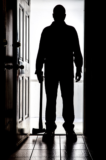 intruder-at-door-in-silhouette-with-axe-picture-id830008050