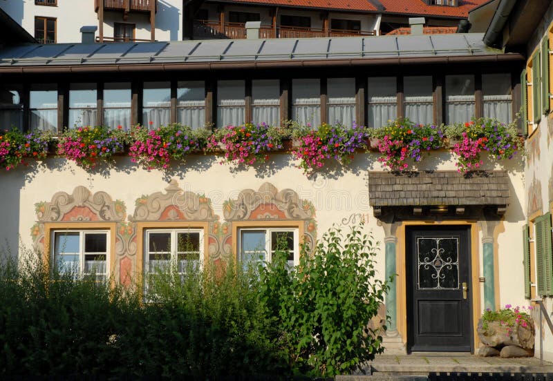facciata-della-casa-con-tre-finestre-e-una-porta-molti-vasi-da-fiori-oberammergau-germania-58358522.jpg